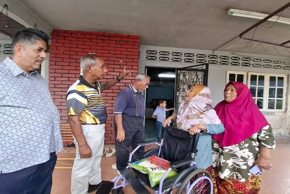 Kulasegaran (dua dari kiri) menyampaikan sumbangan bagi kerja-kerja baik pulih bumbung kepada seorang mangsa ribut, Jumaini Wari, 78, (dua dari kanan) di Kampung Tasek pada Sabtu.