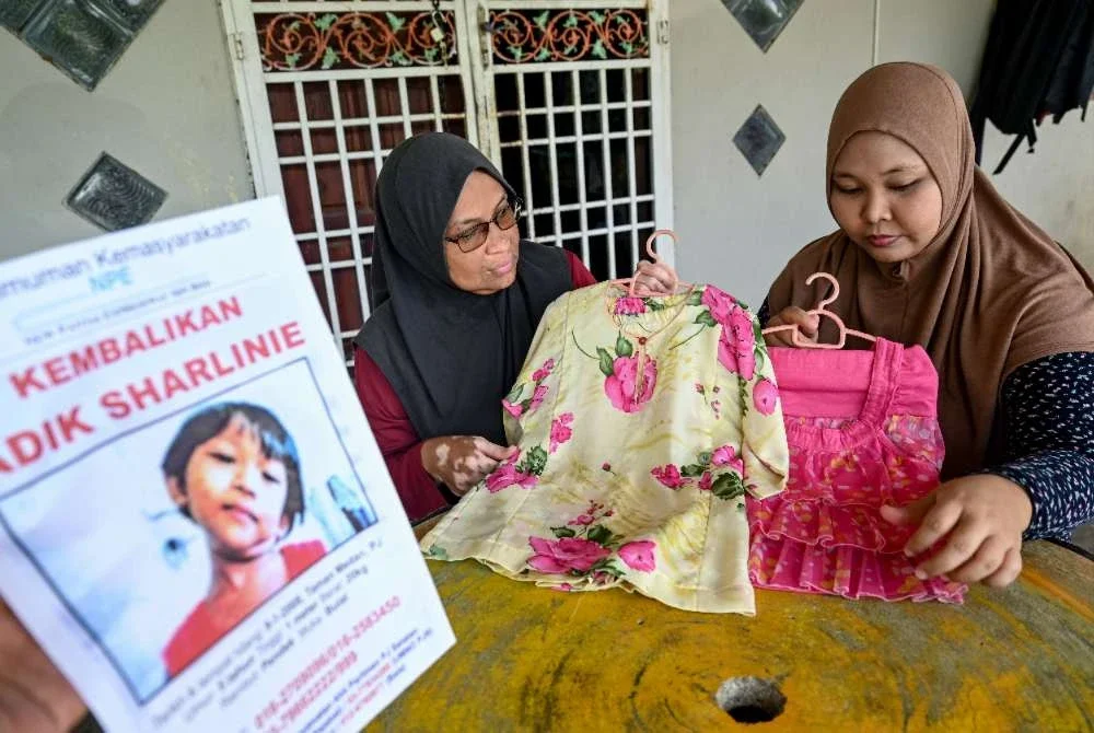 Suraya (dua dari kanan) bersama anaknya, Sharliena Mohd Nashar, 26, menatap baju milik Sharlinie yang sering dipakai selepas hilang hampir dua dekad lalu ketika berusia empat tahun. Foto: Bernama