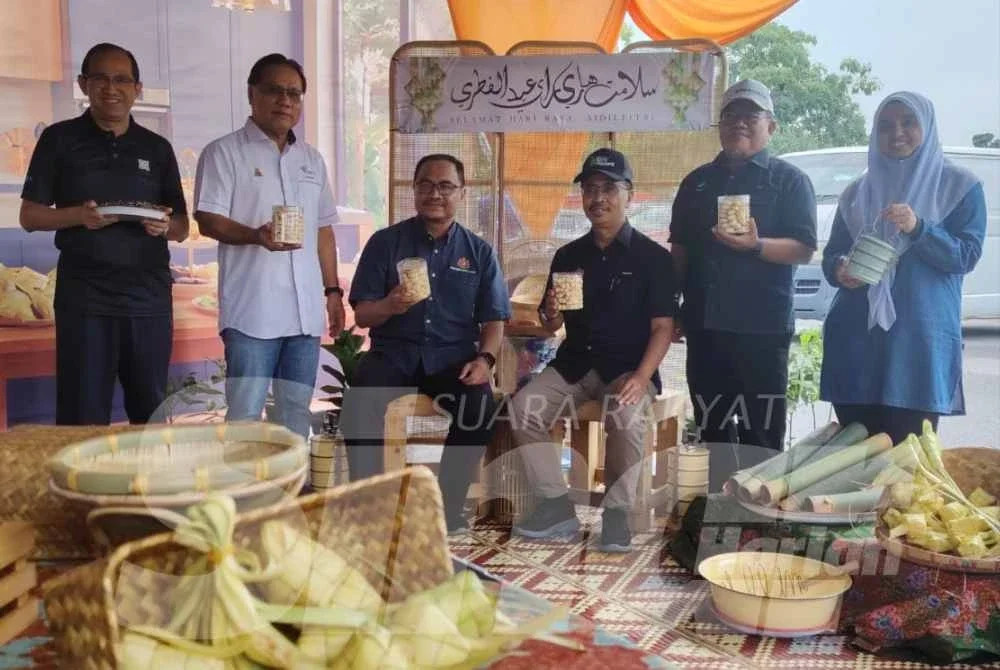 Azli (duduk, tiga dari kiri) dan Abdul Rashid (duduk, tiga dari kanan) menunjukkan balang kuih raya yang dijual pada harga murah