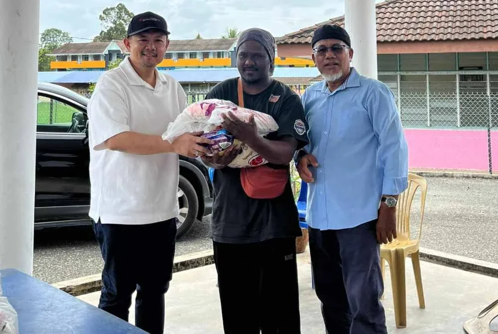 Dr Sharen (kiri) bersama Ahmad Nazlan (kanan) menyampaikan sumbangan kepada salah seorang penerima.