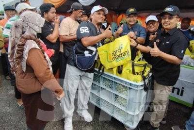 Dari kanan, Abdul Rashid, Isa dan Azli melayan pengunjung yang mendapatkan keperluan harian pada harga RM5 menerusi program Jualan Agro Madani