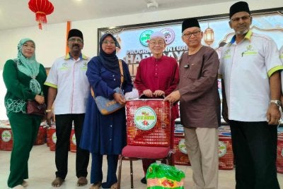 Azizul Kama (dua dari kanan) menyampaikan sumbangan kepada penerima sambil diperhatikan Mohamed Adib (dua dari kiri) sempena Program Bantuan Hari Raya Aidilfitri PRIM di Dewan Masjid Muhammadiah (Masjid Cina Muslim) Tasek pada Ahad.