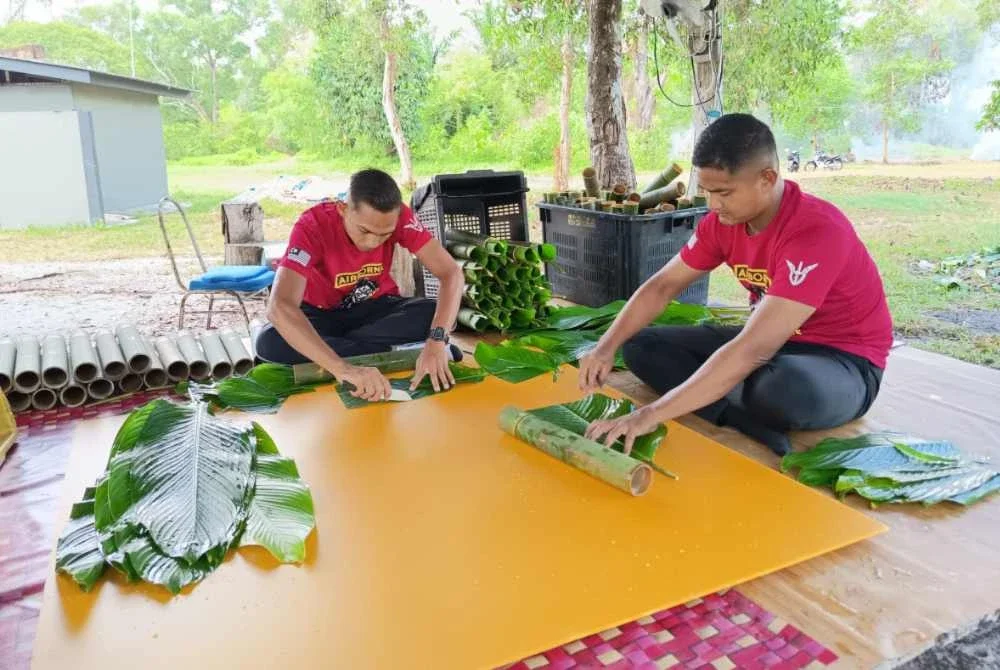 Koperal Wan Ahmad Izwan Wan Mukhtar (kanan) dan Koperal Muhammad Amirul Maidin memotong daun lerek agar sempadan dengan saiz buluh yang disediakan.