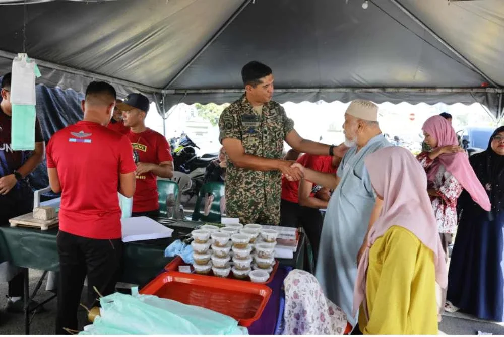 Mohd Ashafiq (tengah) menyantuni pelanggan yang datang untuk mendapatkan lemang di gerai Lemang Tok Singa di Kuala Nerus, Terengganu.