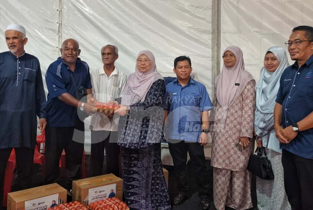 Kamarudin (empat dari kanan) dan Fuziah menyampaikan bantuan barang keperluan asa kepada salah seorang penerima pada selepas merasmikan Jualan Rahmah MADANI Mega Aidilfitri 2026 dan Agihan Wakalah Zakat Korporat SSM di Perkarangan Masjid Sungai Isap Perdana di sini pada Selasa. Foto Sinar Harian