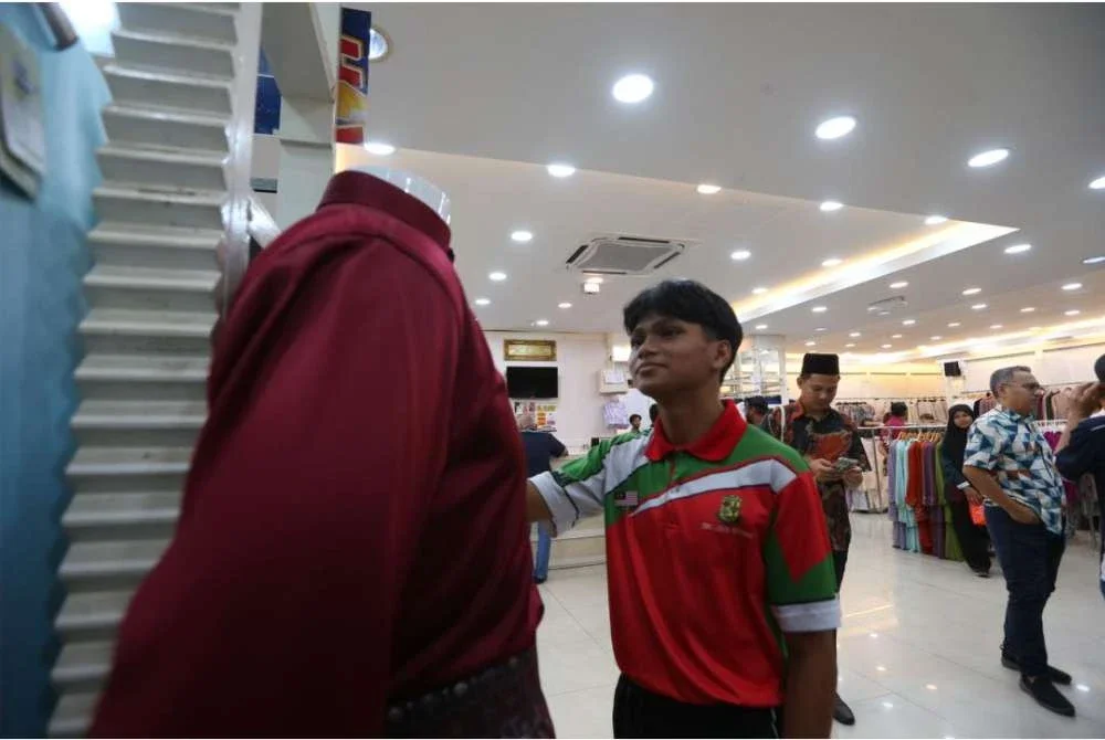 Hafiz mencari baju raya di sebuah gedung pakaian hasil sumbangan Anak Muda Madani Kedah di Alor Setar.