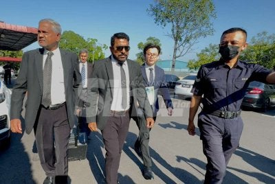 Arun (tengah) meninggalkan Kompleks Mahkamah Majistret Jawi selepas membayar wang jaminan RM5,000 dengan seorang penjamin.