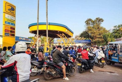 Pemilik kenderaan beratur panjang untuk mengisi minyak di sebuah stesen minyak di Vientiane.- AFP