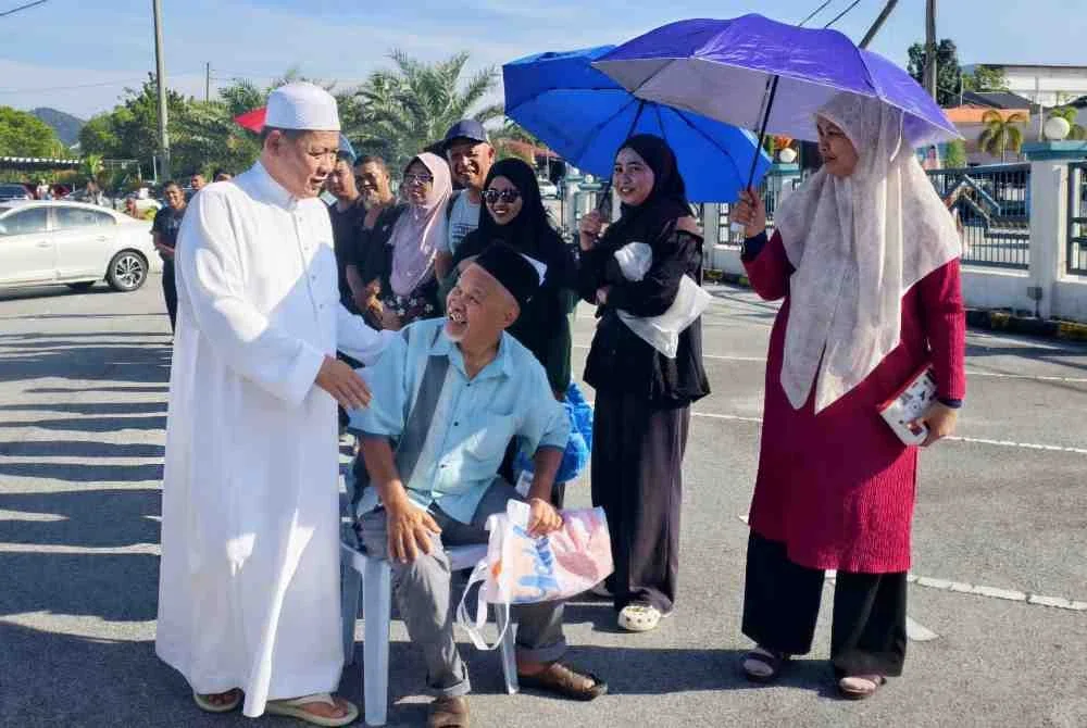 Aminuddin(kiri) beramah mesra dengan pengunjung di Program Mantai Raya DUN Sikamat.