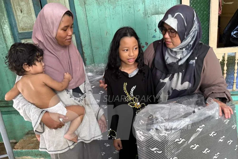 Norain (kiri) bersama dua daripada enam anaknya disantuni Mas Ermieyati yang berkunjung ke rumah itu bagi menyalurkan bantuan.