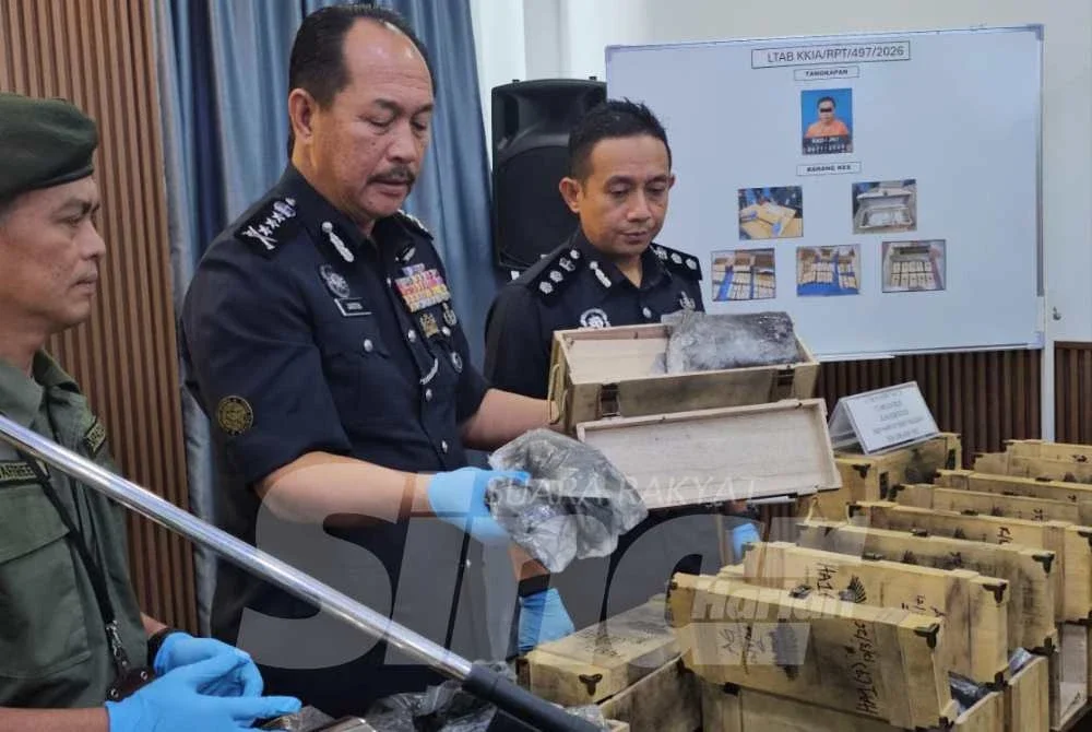 Jauteh (tengah) menunjukkan dadah yang disorokkan dalam bongkah kayu atau kotak botol arak dalam sidang akhbar di IPK Sabah.