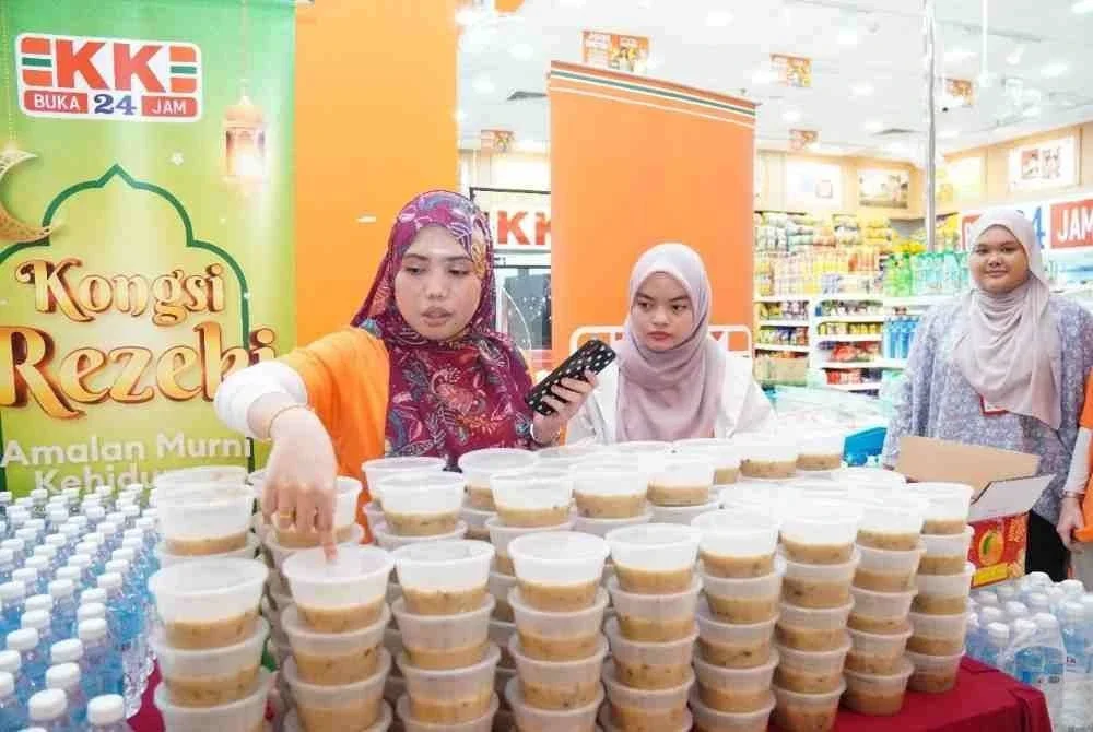 Kakitangan KK MART mengagihkan bubur lambuk kepada penumpang dan pelawat di bangunan Terminal Bersepadu Selatan, Kuala Lumpur.
