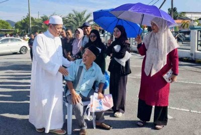 Aminuddin(kiri) beramah mesra dengan pengunjung di Program Mantai Raya DUN Sikamat.