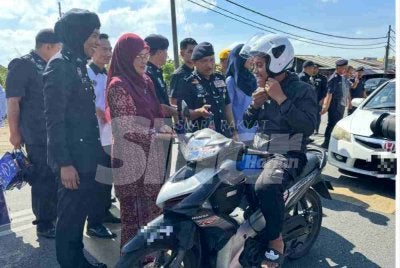 Mohd Yusuff (tiga dari kiri) menyerahkan topi keledar baharu kepada penunggang motosikal.