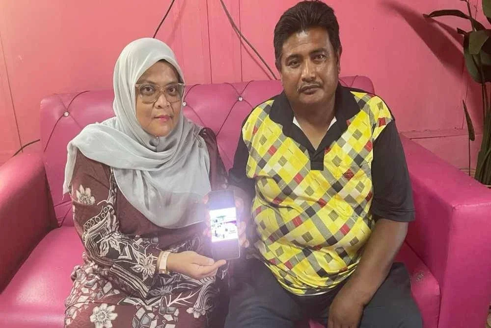 Mohd Noraffizi dan Siti Rumziah menunjukkan gambar kenangan keluarga yang dirakam pada Aidilfitri tahun lalu.
