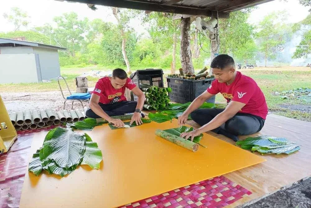 Koperal Wan Ahmad Izwan Wan Mukhtar (kanan) dan Koperal Muhammad Amirul Maidin memotong daun lerek agar sempadan dengan saiz buluh yang disediakan. 