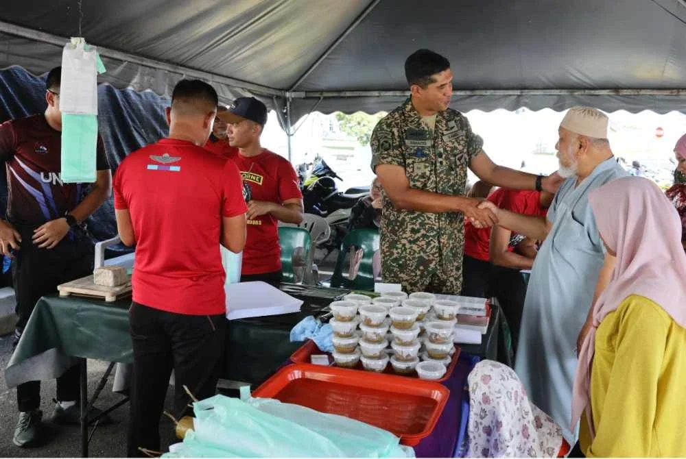 Mohd Ashafiq (tengah) menyantuni pelanggan yang datang untuk mendapatkan lemang di gerai Lemang Tok Singa di Kuala Nerus, Terengganu.