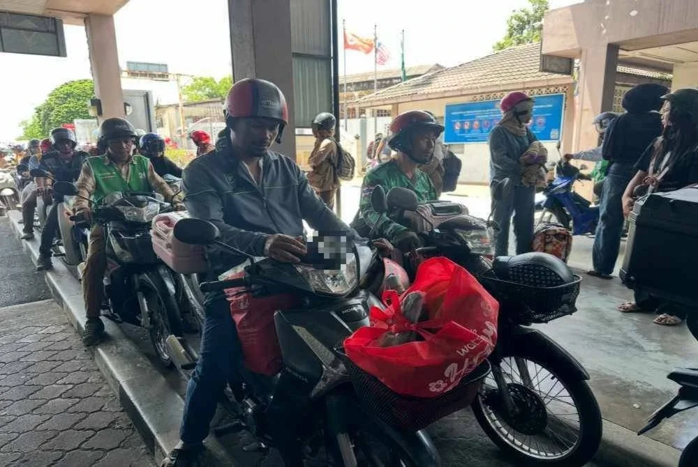 Rakyat Thailand yang selesai mengisi minyak keluar melalui pintu sempadan.
