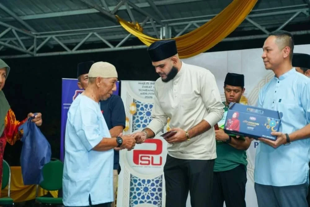 Mohammad Arrief (tengah) menyerahkan sumbangan kepada salah seorang penerima pada Majlis Infak Zakat dan Sumbangan Aidilfitri di PPR Batu Muda di sini pada Rabu.