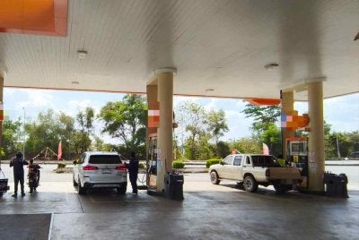 Sebuah kenderaan asing (kanan) mengisi petrol RON97 di sebuah stesen minyak di Bukit Kayu Hitam pada Rabu.