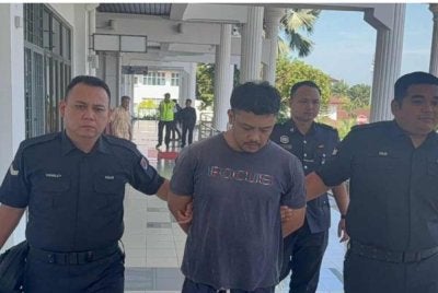 Tertuduh (tengah) ketika dibawa ke Mahkamah Majistret Alor Gajah pada Khamis. 
