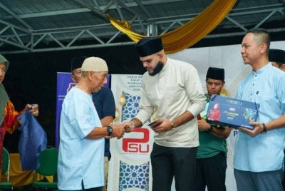 Mohammad Arrief (tengah) menyerahkan sumbangan kepada salah seorang penerima pada Majlis Infak Zakat dan Sumbangan Aidilfitri di PPR Batu Muda di sini pada Rabu.