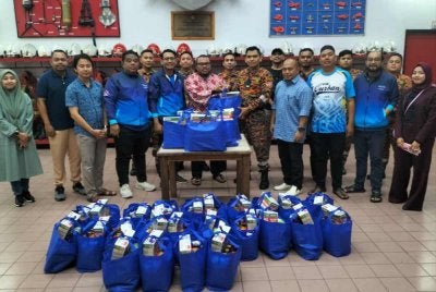 Izzat menyampaikan pek makanan tajaan Nestle kepada Pegawai Bomba Kanan II, Balai Bomba Seksyen 17, Syafiq Mohd Shukri.