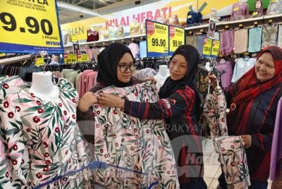 Nurin Amira Aleya (kiri) dibantu Zuraini (tengah) semasa memilih baju raya di pasar raya Mydin di Alor Setar.