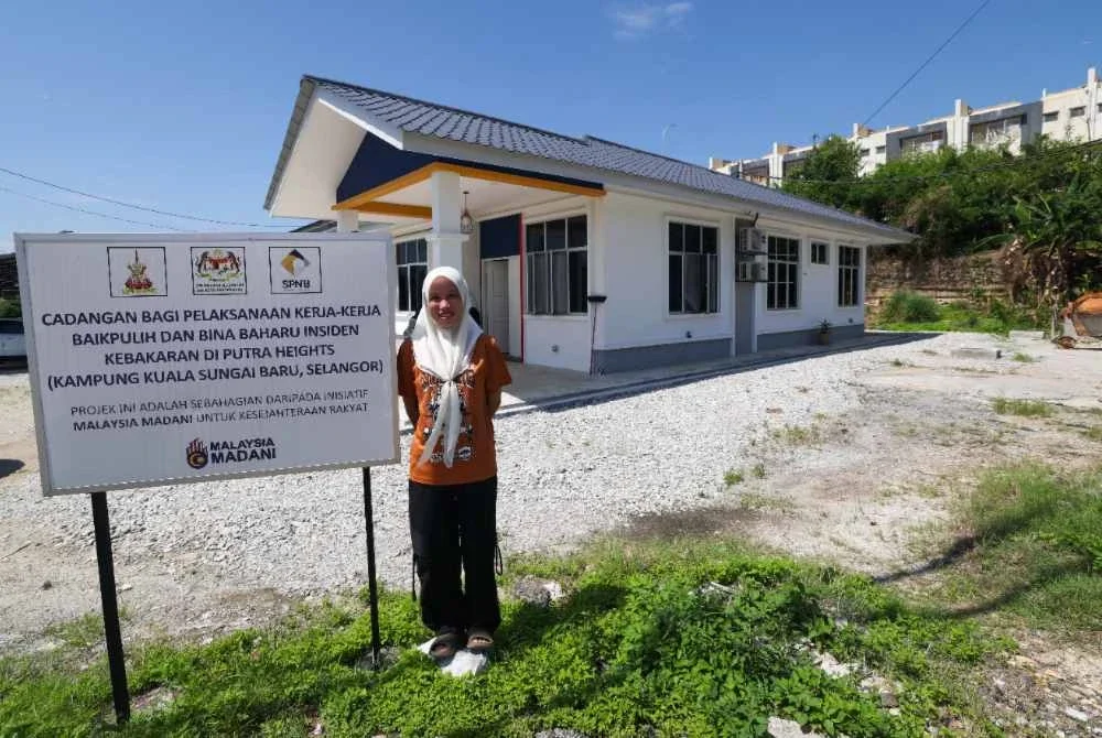 Nurul Adawiyah di hadapan rumah baharu selepas rumahnya musnah akibat tragedi letupan gas tahun lepas. Foto Bernama