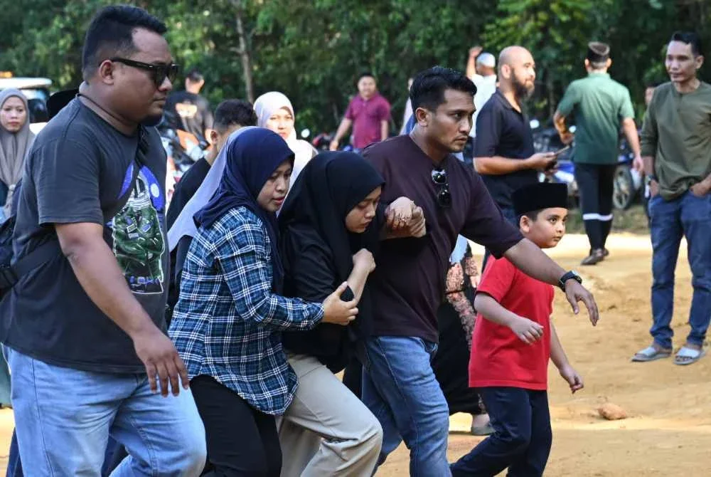 Adik mangsa, Nurul Izzah Shaary (tengah) tidak dapat menahan sebak ketika pengebumian kakaknya bersama dua anaknya di Tanah Perkuburan Islam Kampung Sungai Tong, Setiu pada Selasa. Foto Bernama