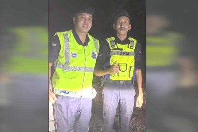 Dua anggota polis yang membantu mengiring sebuah keluarga selepas anak perempuan mereka tertinggal di Hentian Rehat Sungai Merab pada Isnin.