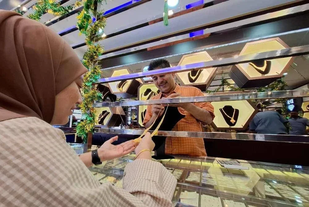 Amaluddin menunjukkan koleksi barangan kemas yang terdapat di kedainya kepada Khairun Nisa sewaktu tinjauan Sinar Harian pada Selasa.