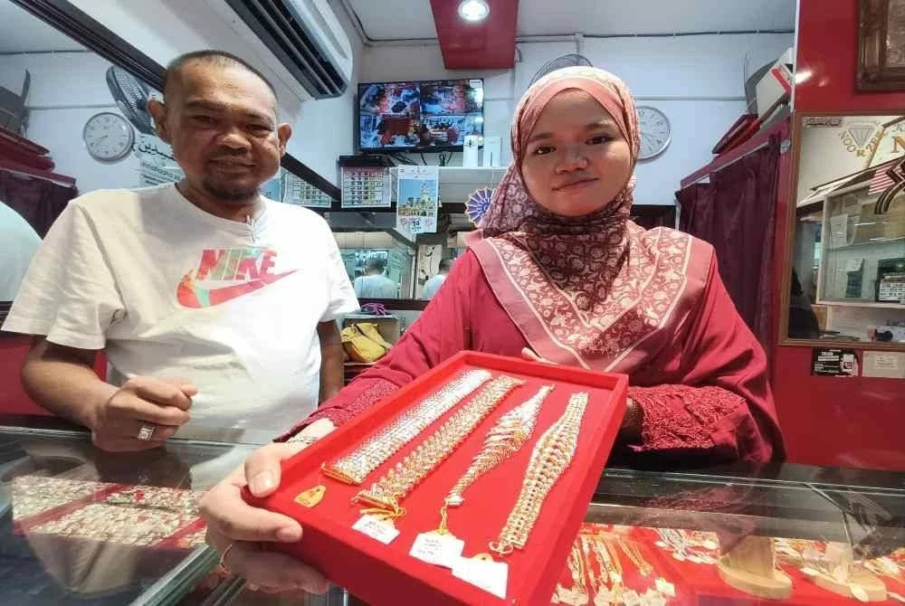 Syakir Hilmi (kiri) menunjukkan antara koleksi barangan kemas terkini yang menjadi buruan pelanggan.