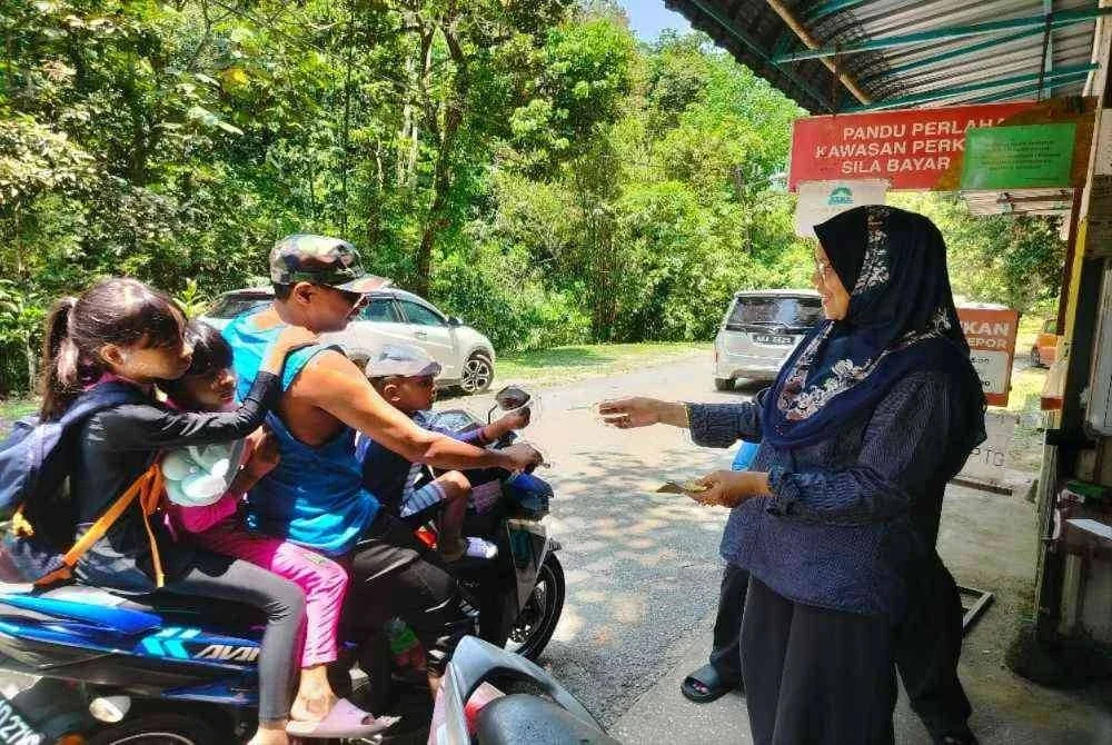 Aisah memberikan resit bayaran kepada pengunjung yang masuk ke kawasan Lata Ulu Chepor di sini pada Rabu.