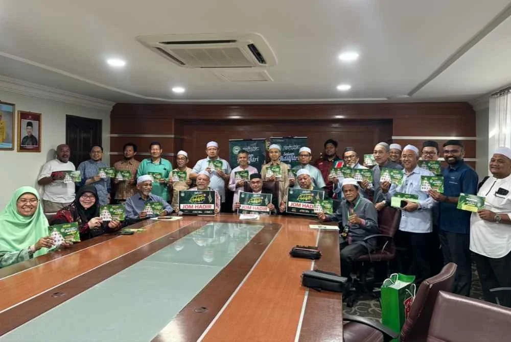 Pihak penganjur memegang risalah dan kad jemputan untuk orang ramai hadir ke rumah terbuka sempena perayaan.
