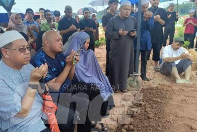 Md Nazry (duduk, dua kiri) bersama ahli keluarganya membaca doa di Tanah Perkuburan Islam Seksyen 19, Shah Alam.
