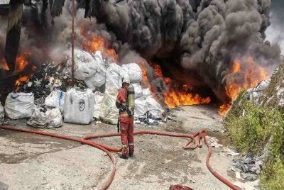 Anggota bomba sedang memadamkan kebakaran longgokan barangan kitar semula, pada Khamis.