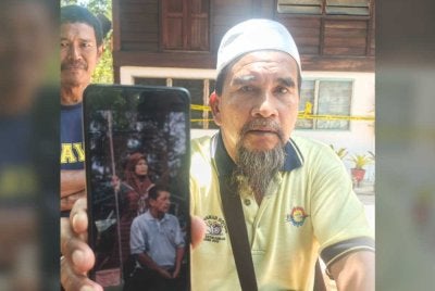 Hashim menunjukkan gambar Zikri bersama arwah isterinya semasa ditemui di lokasi kejadian pada Khamis.