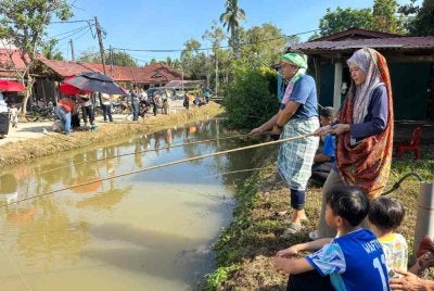 Azhari (kiri) dan Suria Hazleen (kanan) bersama-sama menunggu ikan memakan umpan.