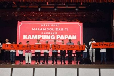 Tony (tengah) dan Arutchelvan (lima dari kanan) memegang kain rentang solidariti semasa Majlis Malam Solidariti Penduduk Kampung Papan pada Sabtu.