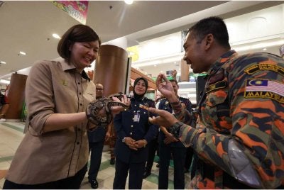 Sandrea (kiri) memegang seekor ular sawa dalam Program Kesedaran Keselamatan Awam sempena Program Satelit Program Madani Rakyat anjuran JBPM Perak di AEON Mall Kinta City di Ipoh pada Ahad.