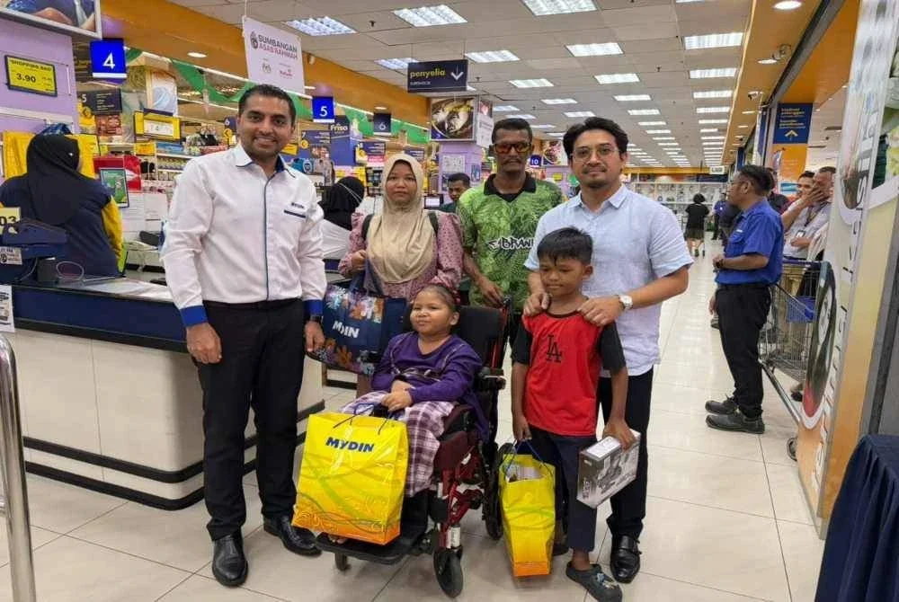 Mohd Zaidy (kanan) dan Azmin (kiri) menyantuni Nur Umairah dan keluarganya membeli kelengkapan di Pasar Raya Besar Mydin, Taman Saga di Alor Setar.