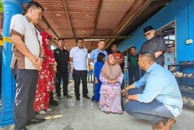 Mohd Noor Helmy (kanan) bersama agensi menyantuni Makcik Fatimah yang rumahnya terbakar pada Sabtu lalu.