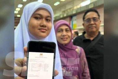 Nur Syahirah Syazwani (kiri) menunjukkan keputusan SPM 2025 yang diperolehinya.
