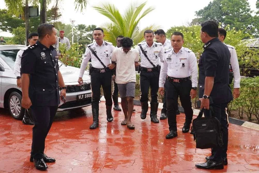 Suspek berusia 20-an, memakai baju T berkolar warna putih, tiba di Mahkamah Majistret Klang pada Rabu, dengan diringi pihak polis. Foto: ROSLI TALIB