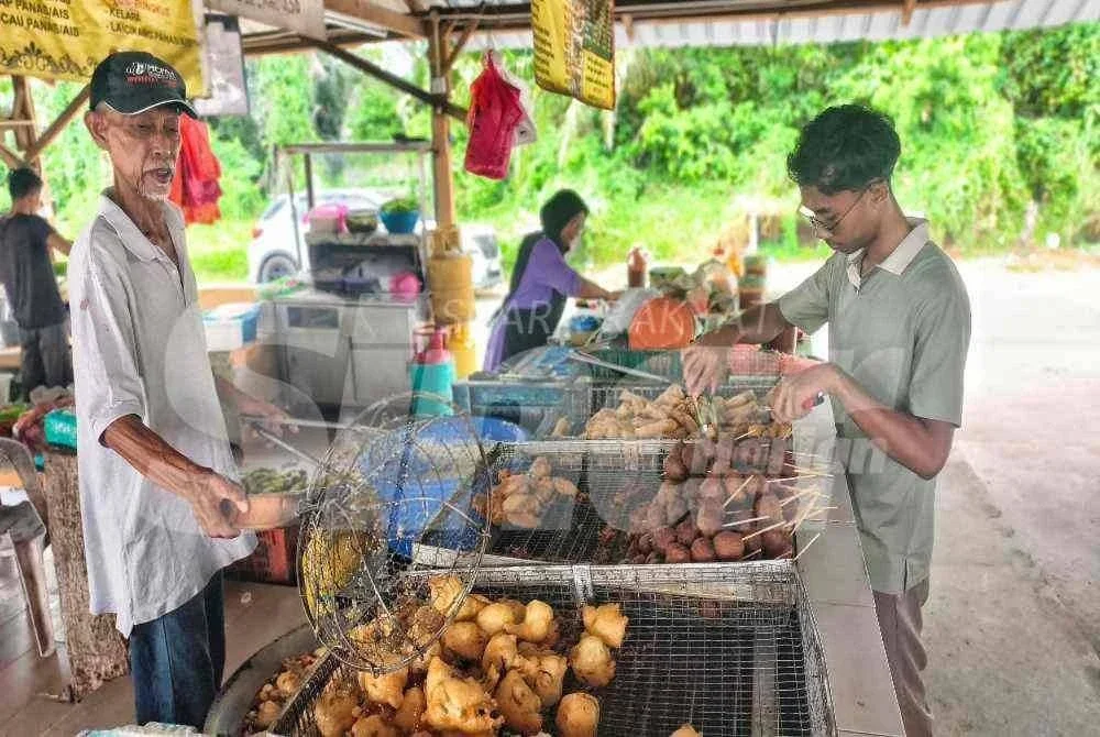 Fakhrul Iman (kanan) tidak kekok membantu ibu bapanya di gerai mereka.