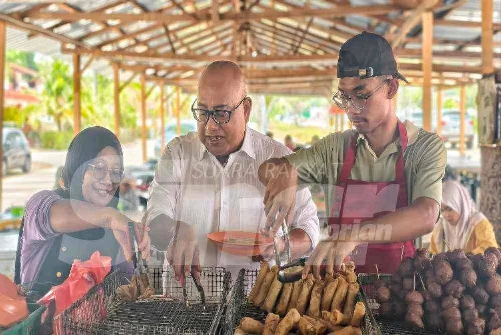 Mohd Faizal (tengah) melayan Mohd Faizal yang datang melawatnya di gerai.