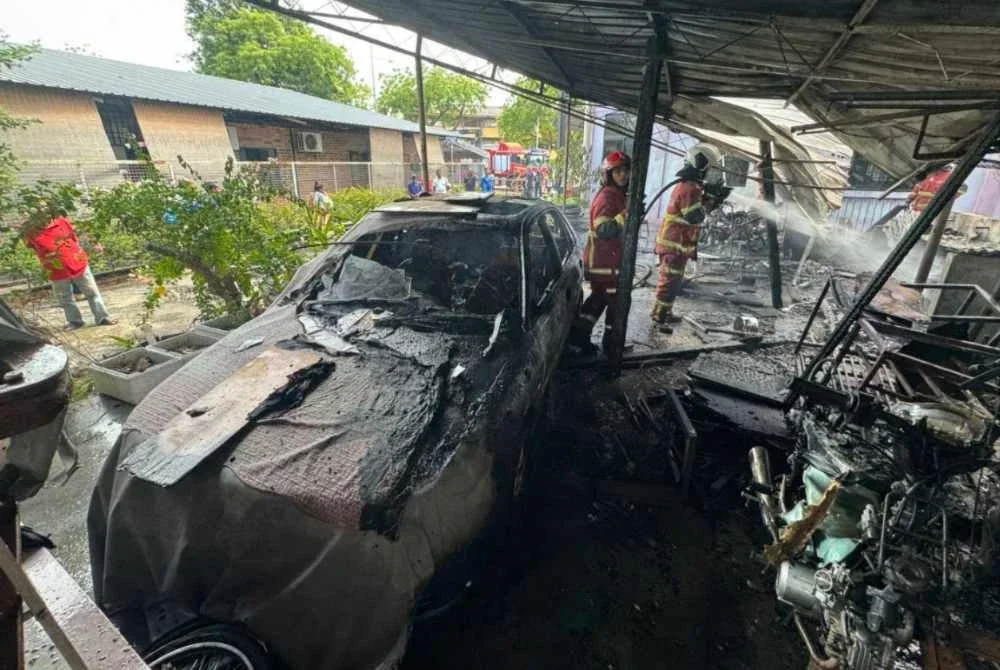 Anggota bomba sedang memadamkan kebakaran di bengkel berkenaan.
