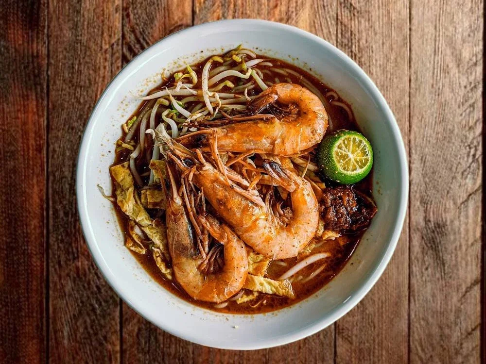Laksa Sarawak yang kaya rasa, dihiasi udang segar, tauge rangup dan perahan limau, menggamit selera dengan kuah berempah yang memikat.