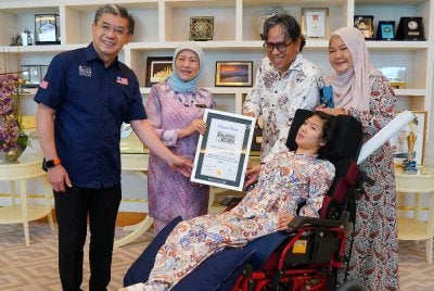 Christopher (kiri) menyerahkan sijil MBOR kepada Nur Wadihan sambil disaksikan Nancy dalam majlis ringkat di Kementerian Pembangunan Wanita, Keluarga dan Masyarakat di Putrajaya pada Rabu.
